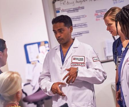 A photograph with blurred edges of several Fox Chase medical professionals huddling together to discuss something.