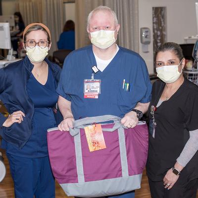 Three nurses, one man and two women, with a Chemo comfort bag