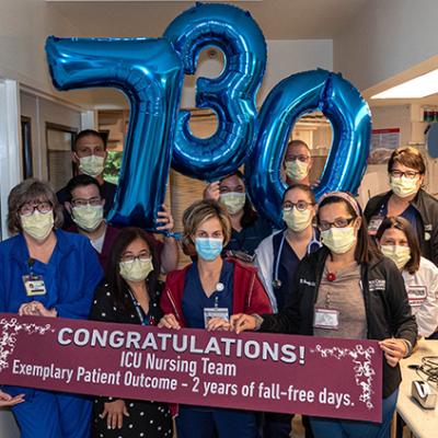Group of nurses with 730 number balloons and Congratulations sign for 2-year of fall free days.