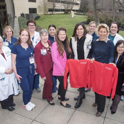 Group of nurses with two nurses holding red Temple sweatshirts