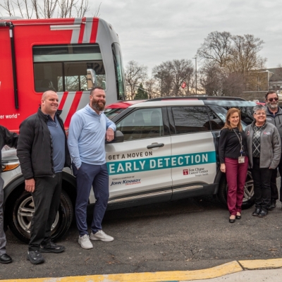 A group of seven people stand beside a Fox Chase Cancer Center–Temple Health vehicle and a large mobile cancer screening bus