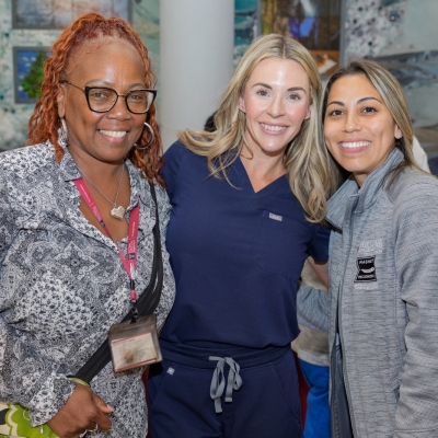 Three women smile and pose together