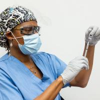 A photograph of a medical professional using a syringe to extract something from a vial.