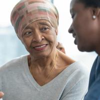 A photograph of two people sitting closely together, smiling and gesturing at a tablet in their hands.