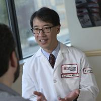 A Fox Chase doctor smiles as they speak with a patient, sitting across from each other in front of a window.