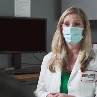 A photograph looking over a patient's shoulders as they sit on the other side of a desk from a Fox Chase doctor.