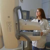 A photo of a medical professional looking at a mammogram machine.
