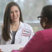 A photo of a Fox Chase doctor sitting across from a patient, smiling and holding a paper in their hands.
