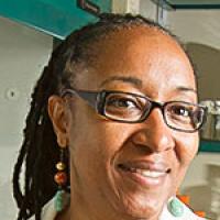 A close up portrait shot of Camille Ragin, smiling at the camera with her head turned slightly to the side.