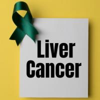 A paper reading &quot;Liver Cancer&quot; in bold black lettering with a green ribbon atop the corner, set on a yellow background.