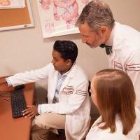 Dr. Sanjay Reddy gestures at a screen as he discusses a particular case with other Fox Chase doctors and specialists.