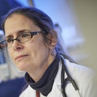 A close up photo of a medical professional looking off camera, with the right half of the image obscured.