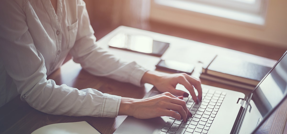 A photo with heavy post processing of a person sitting at a desk using a laptop.