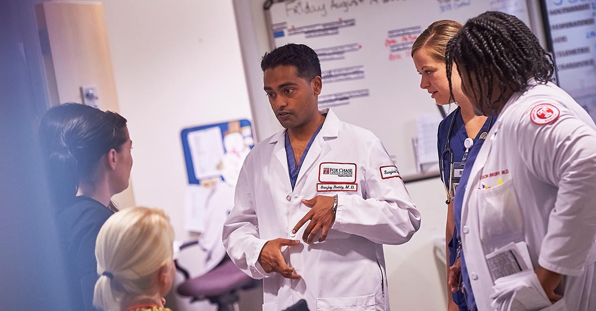 A photograph with blurred edges of several Fox Chase medical professionals huddling together to discuss something.